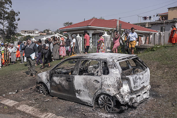 Over 20 k*lled in two mass sh*otings in South Africa 4 Residents stand near a vehicle owned by one of the victims was set ablaze by unknown gunmen at the scene of a mass shooting in the Ziko area of KwaMakhutha, south of Durban on September 23, 2026